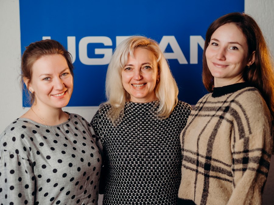 Отдел поставок UGRAN — сотрудницы на фоне логотипа